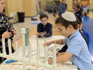 A boy builds a pvc menorah at the carnival