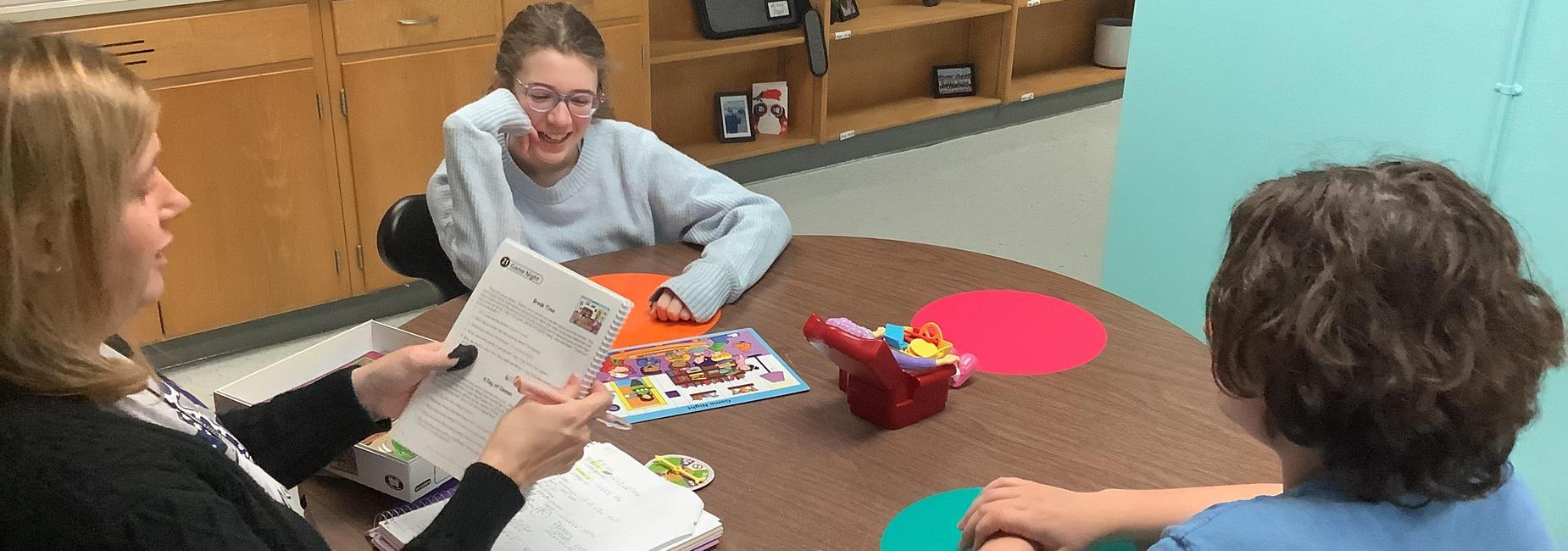 A group activity with two children and an adult engaging at a table with games.