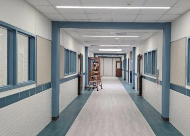 Long, newly constructed hallway with blue accents and a ladder.