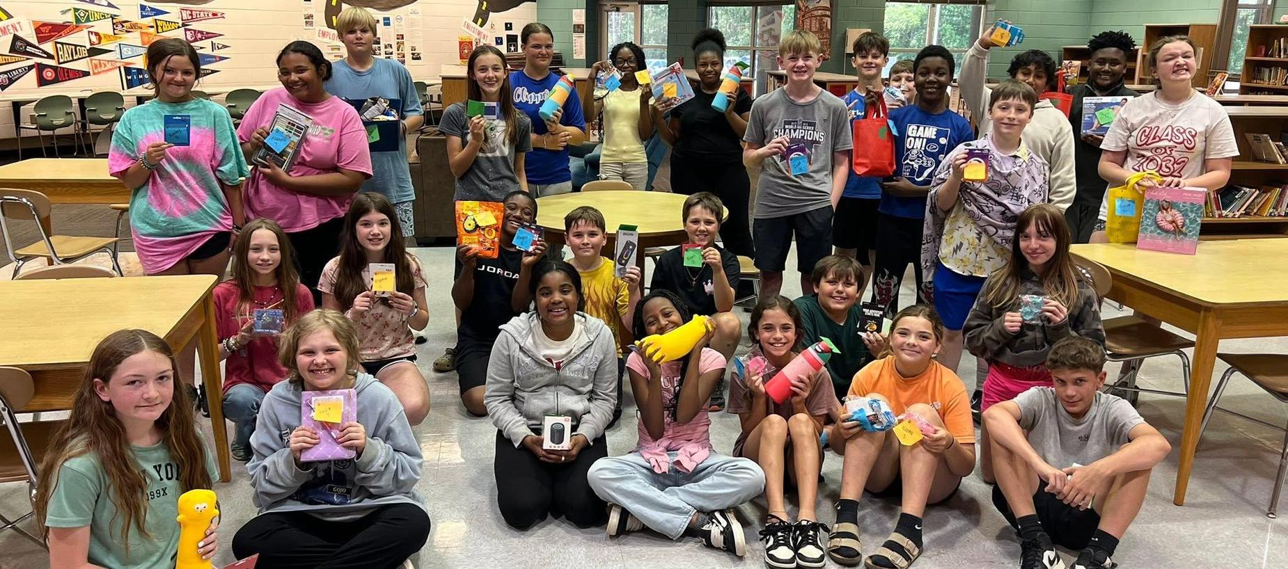 Group of students holding colorful cards, gathered in a school library.