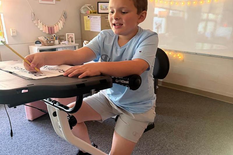 student rides stationary bicycle
