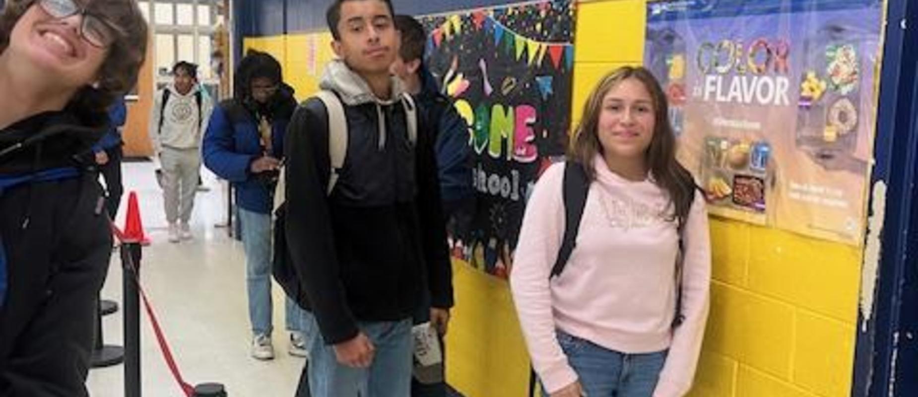 Students waiting in line at a school hallway with colorful decorations.