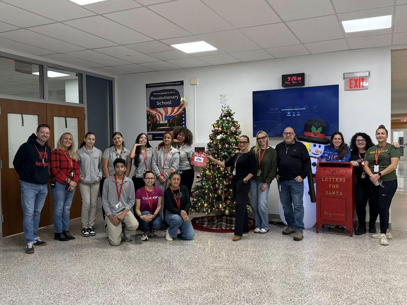 students and staff in front of a christmas tree