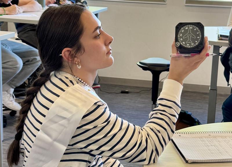 Teenage girl looks at flight equipment in a classroom