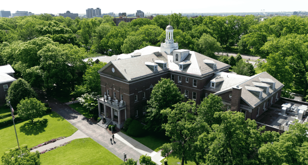 Aerial view of a historic building surrounded by lush trees and green space.