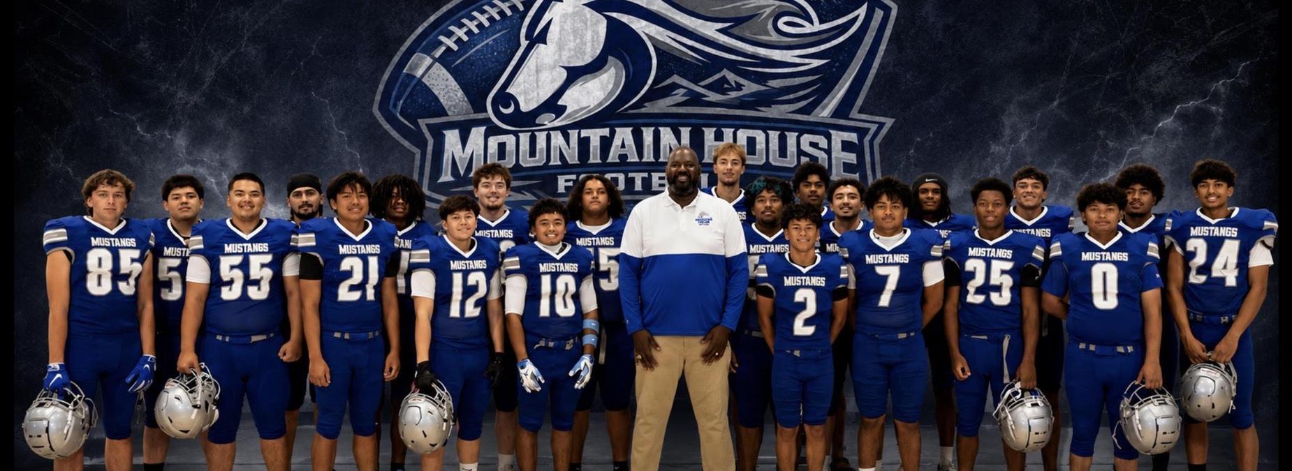 A football team in blue uniforms poses for a group photo with their coach.