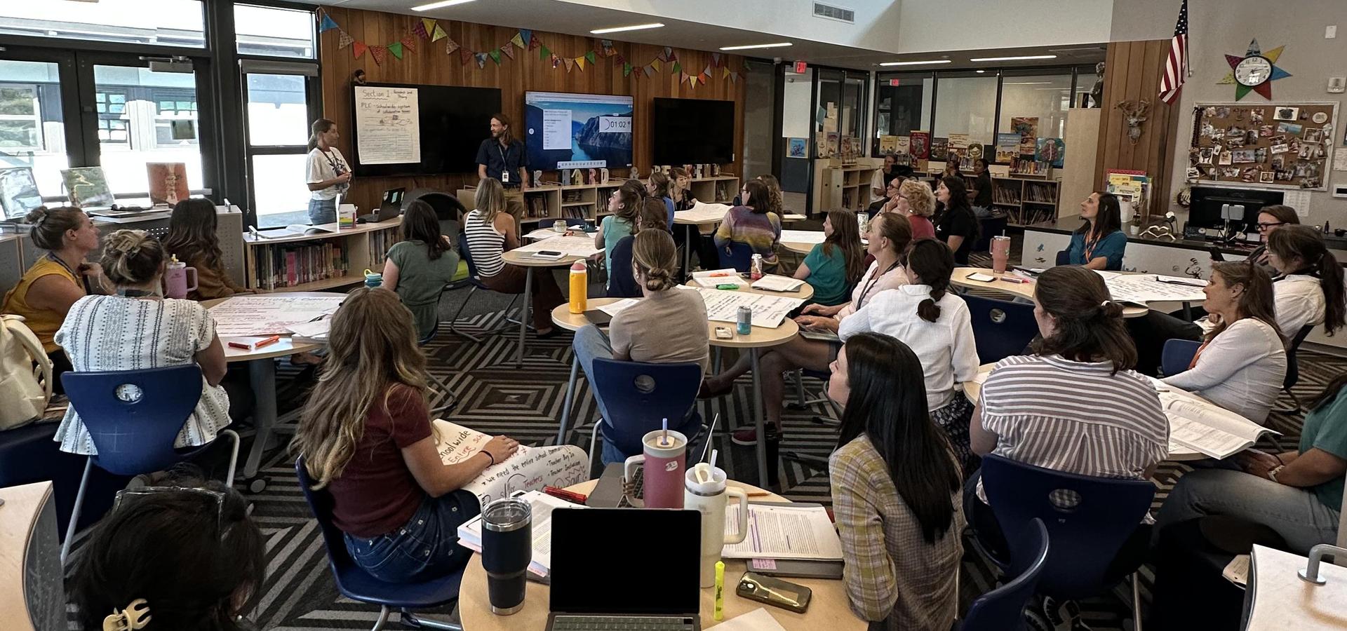 A group of adults engaged in a workshop inside a library classroom setting.