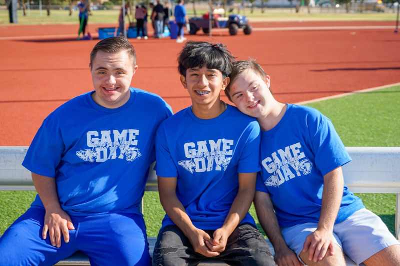 Three Frenship High School special education students sitting on a bench and smiling.