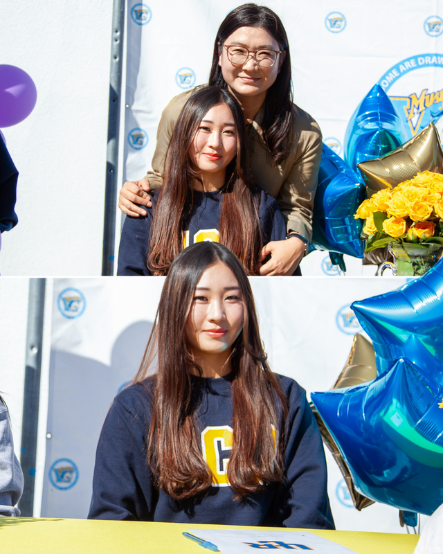 Smiling woman and girl pose together with flowers and balloons in a festive setting.