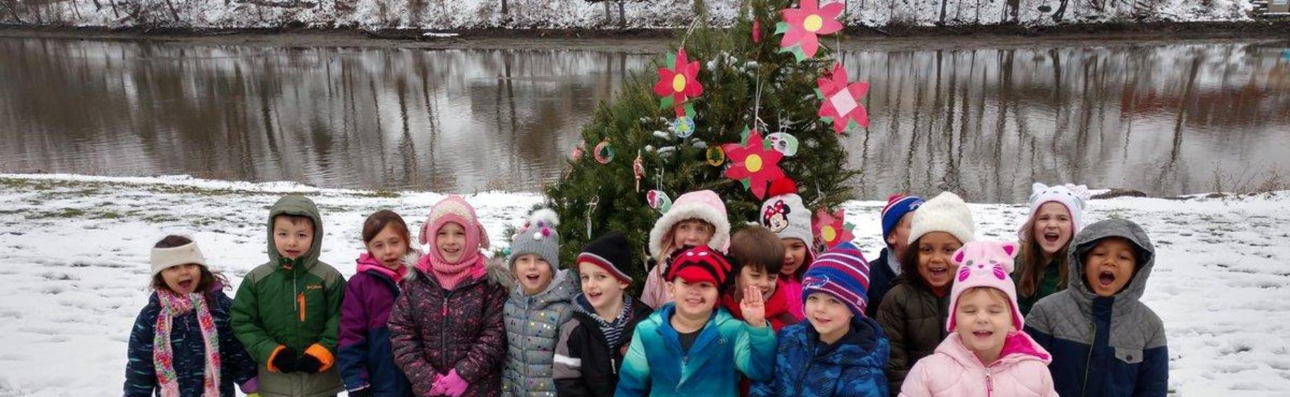 Students with decorated tree on creekbank