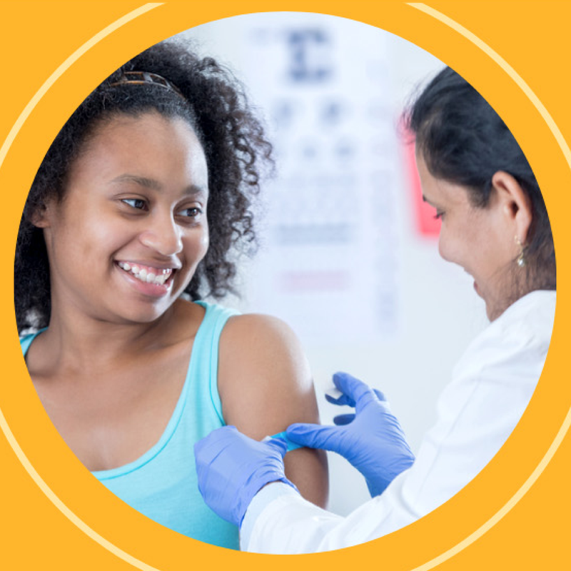 A young woman smiles widely as she receives a Covid-19 vaccine