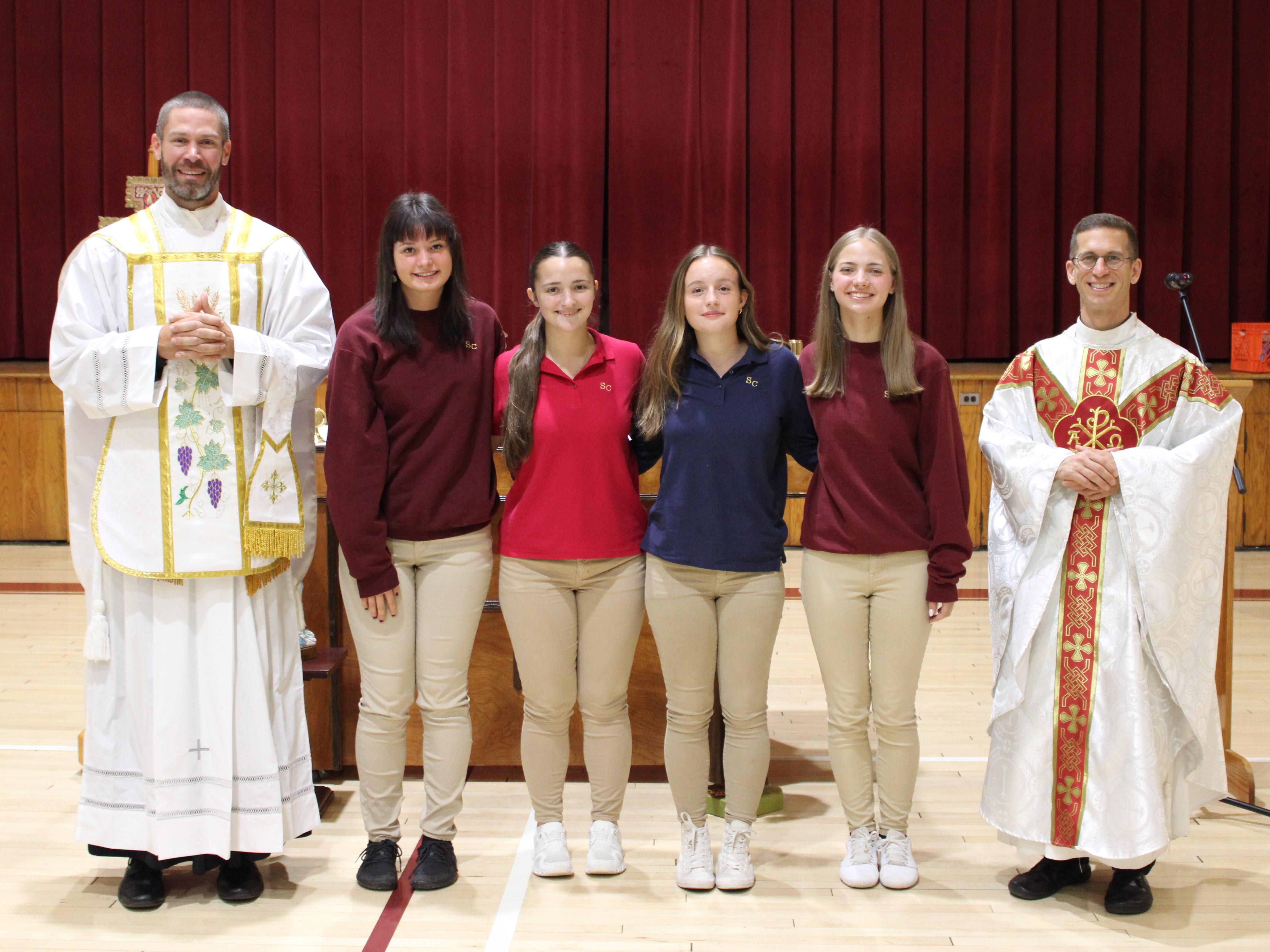 Students stand with chaplain and co-chaplain after Mass.