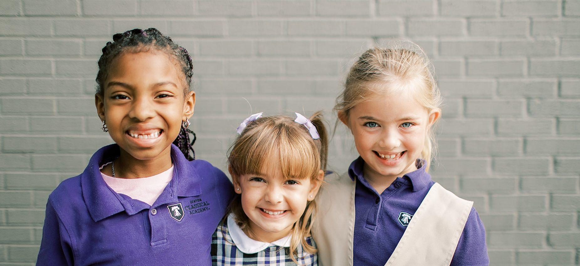 Three smiling young students stand together
