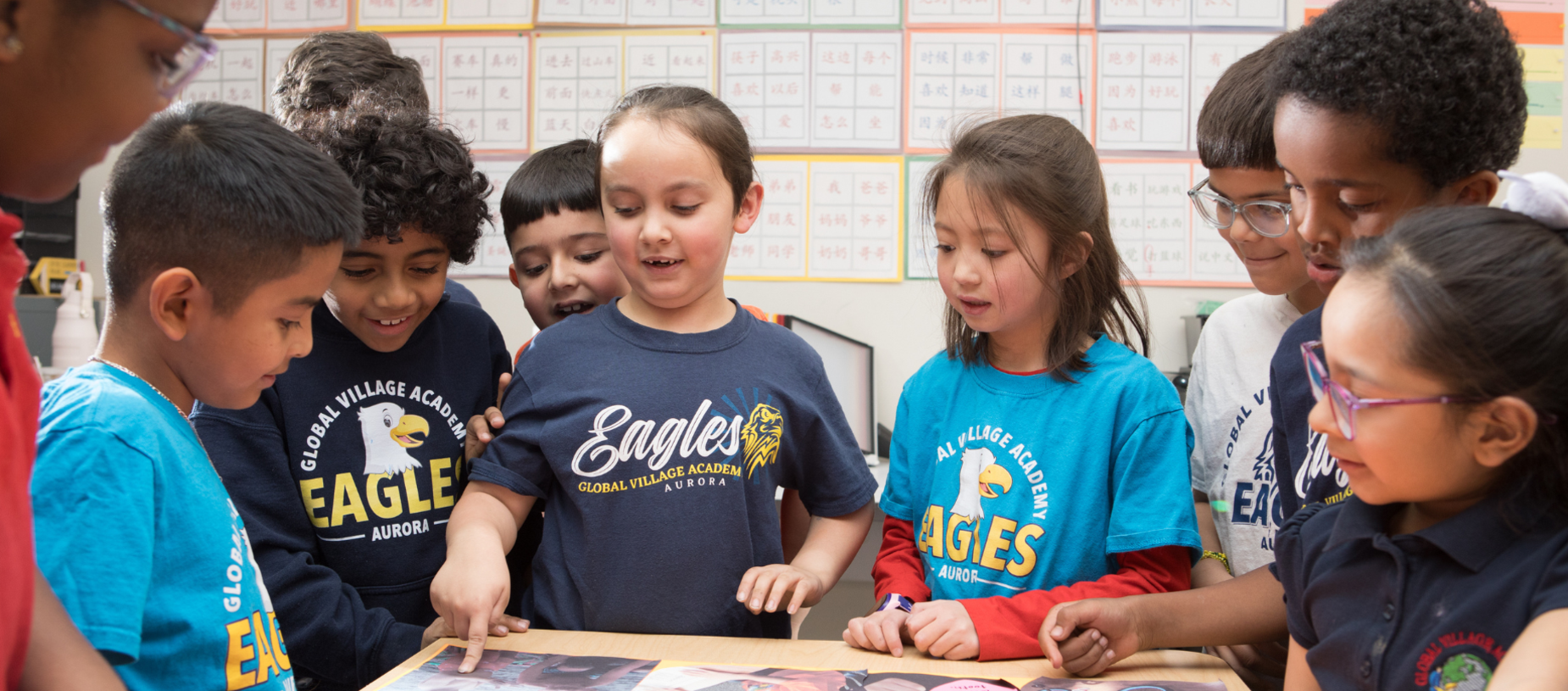 A diverse group of children gathered around a table, engaging with materials and smiling.
