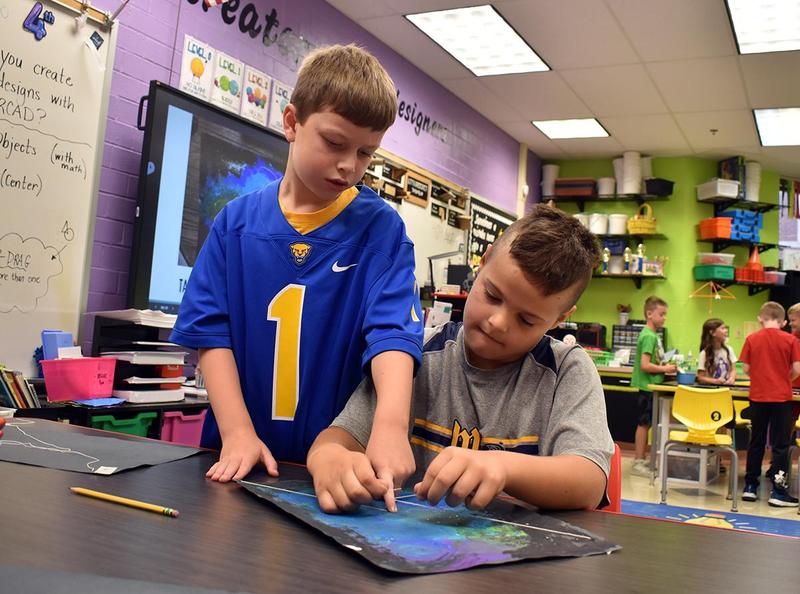 two boys tying a piece of string