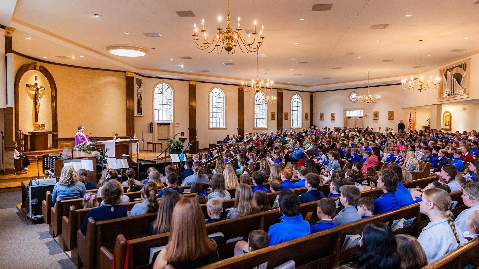 A large group of people seated in a church during a service, with a band performing.