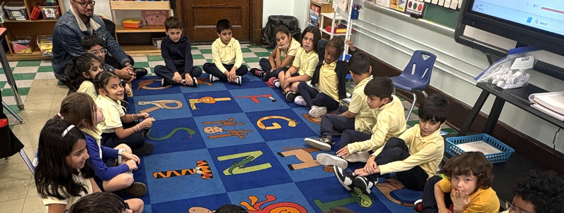 Classroom with children sitting on a colorful rug, engaged in a group activity.