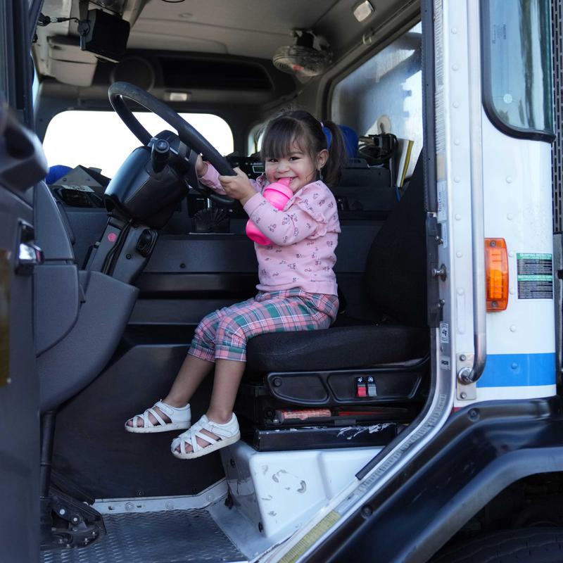Small girl sitting in driver's seat of CR&R Trash Truck
