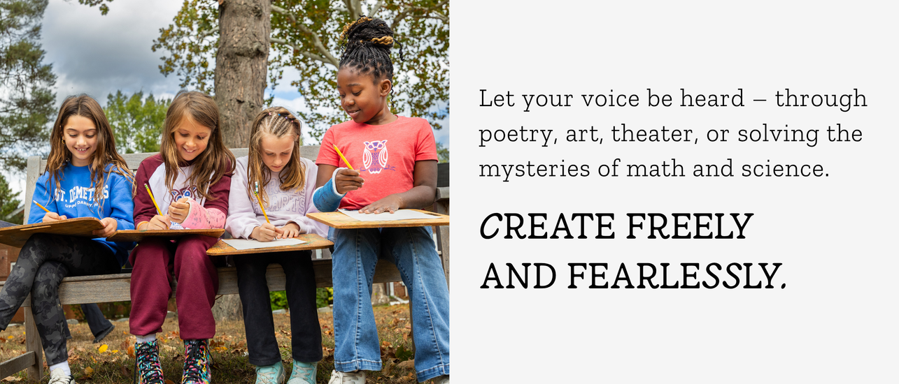 Four girls sitting together outdoors, writing in notebooks, with trees in the background.