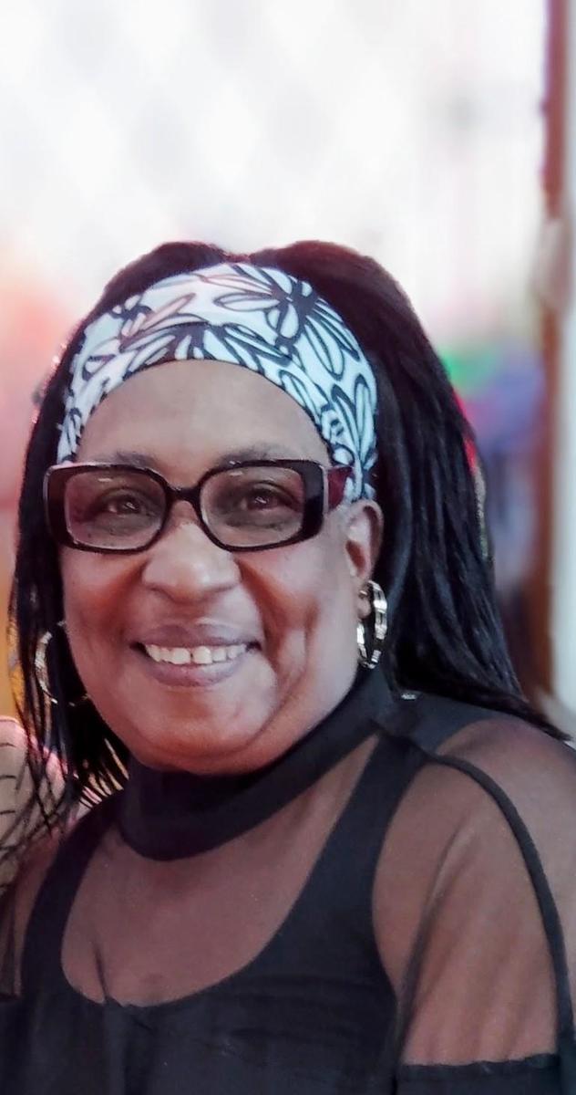 Cheerful woman wearing a headscarf and glasses, smiling at the camera.