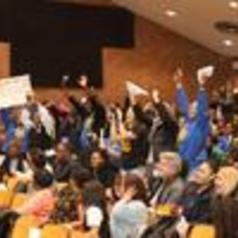 A crowd of people with raised hands in a meeting or event setting.