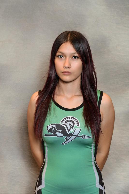 female athlete poses with arms behind back with grey backdrop