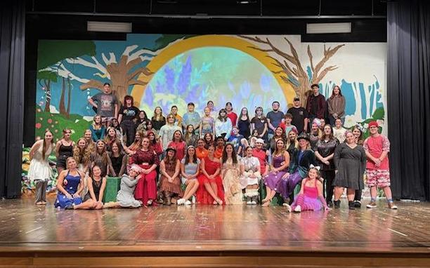 Alice in Wonderland (and Back Again) cast and crew posing on stage for a group picture.
