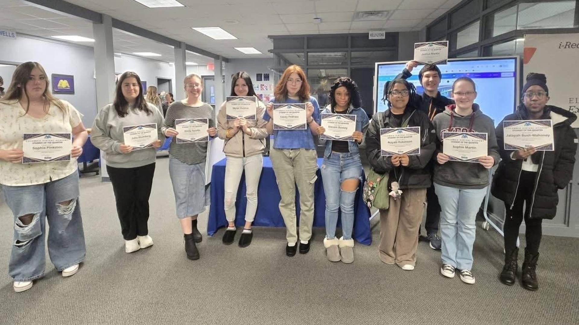 Group of students holding certificates in a school environment.