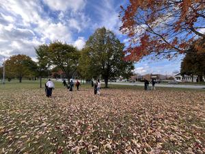 Group of students collecting trash in a park among fallen leaves.