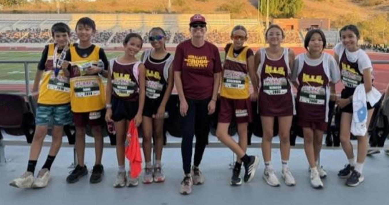 Group of young runners posing together at an outdoor event.