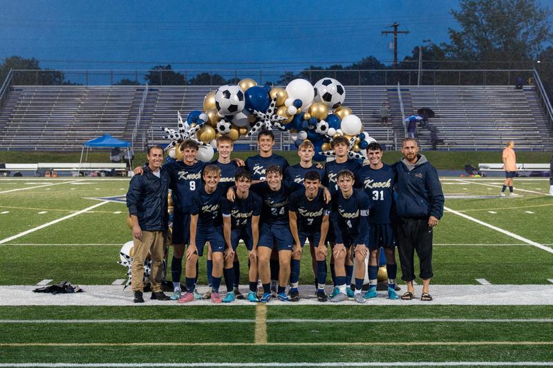 group of boys dressed in uniforms posed on a soccer field