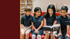 Four students read a book together on a red couch