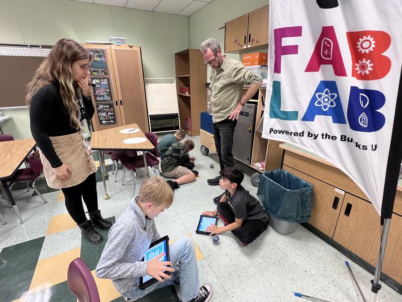 Two teachers helping students code robots using iPads