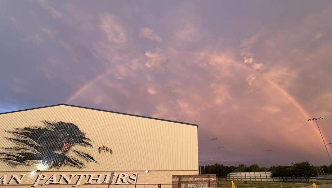 A colorful rainbow arcs over a sports facility featuring a panther logo.