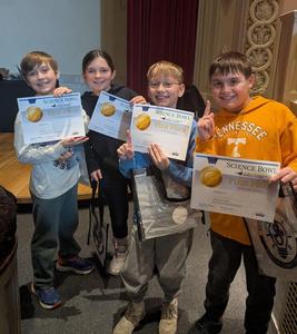 A team of four students holding up their first place certificates at the museum.