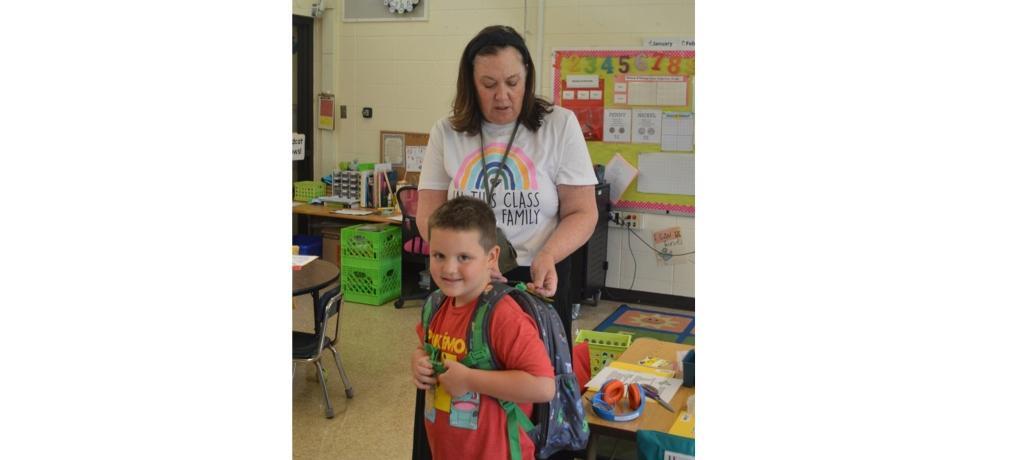 Teacher affixes ID to student's backpack.