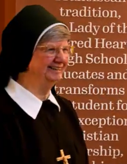 Sr. Lee stands in the OLSH hall greeting students