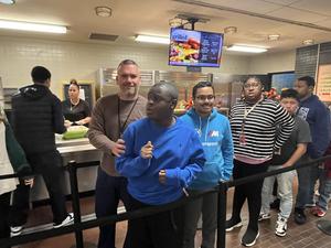 Students and staff member in line for lunch