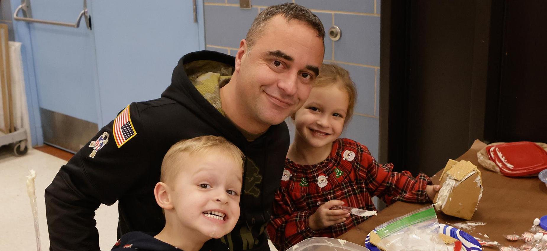 A smiling man and two children enjoying a crafting activity together.