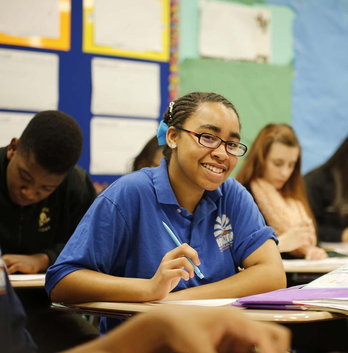 Student writing in a classroom.