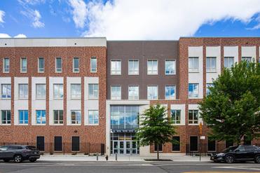 Modern brick building with large windows and trees in front.