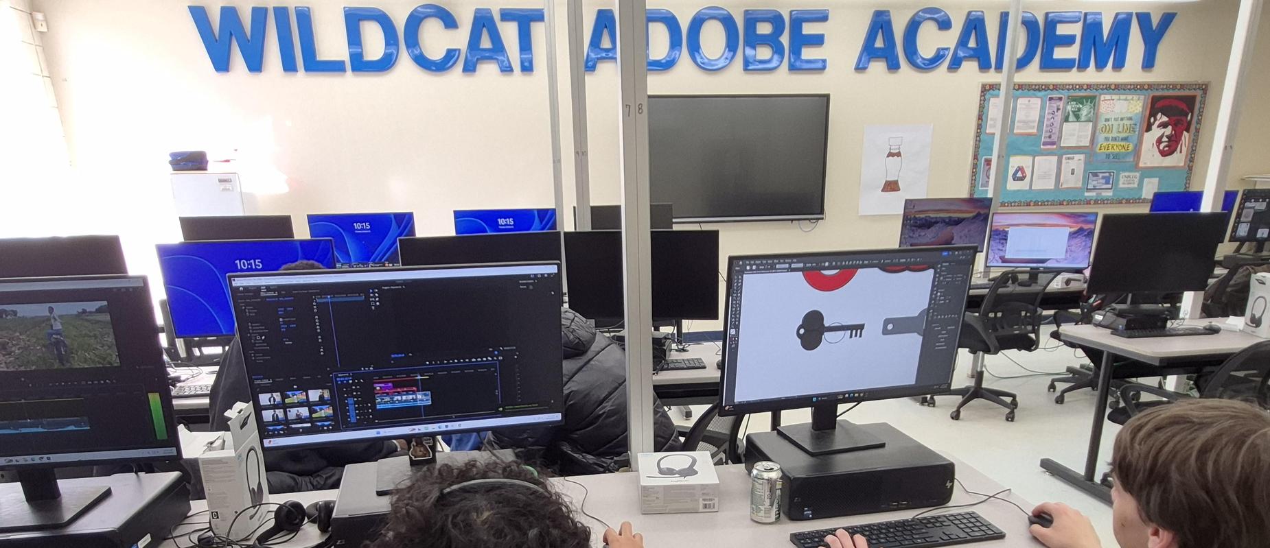Students working on computers in a classroom with editing software open.