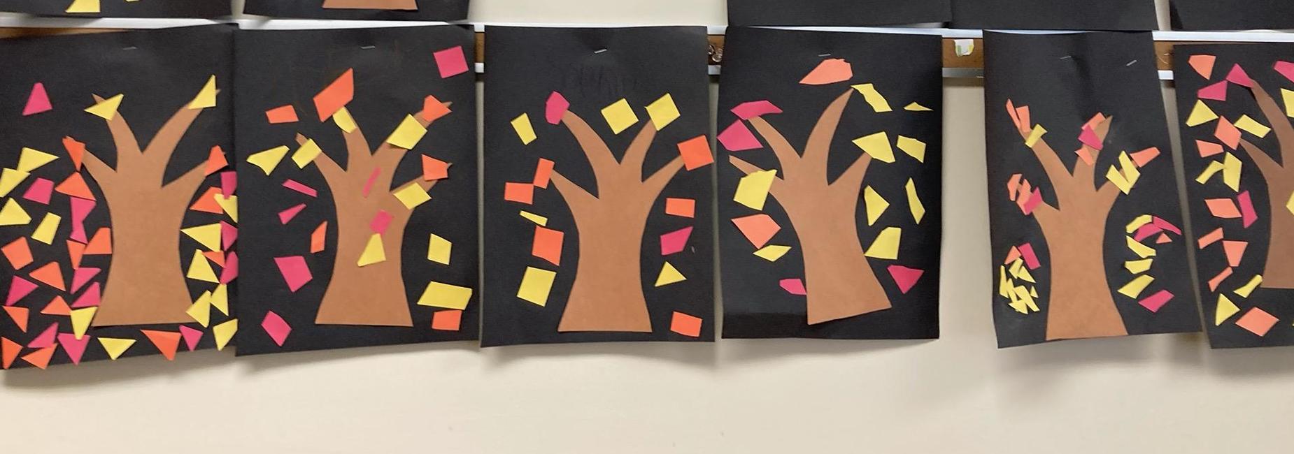 Student created artwork of trees with red, orange, and yellow leaves falling