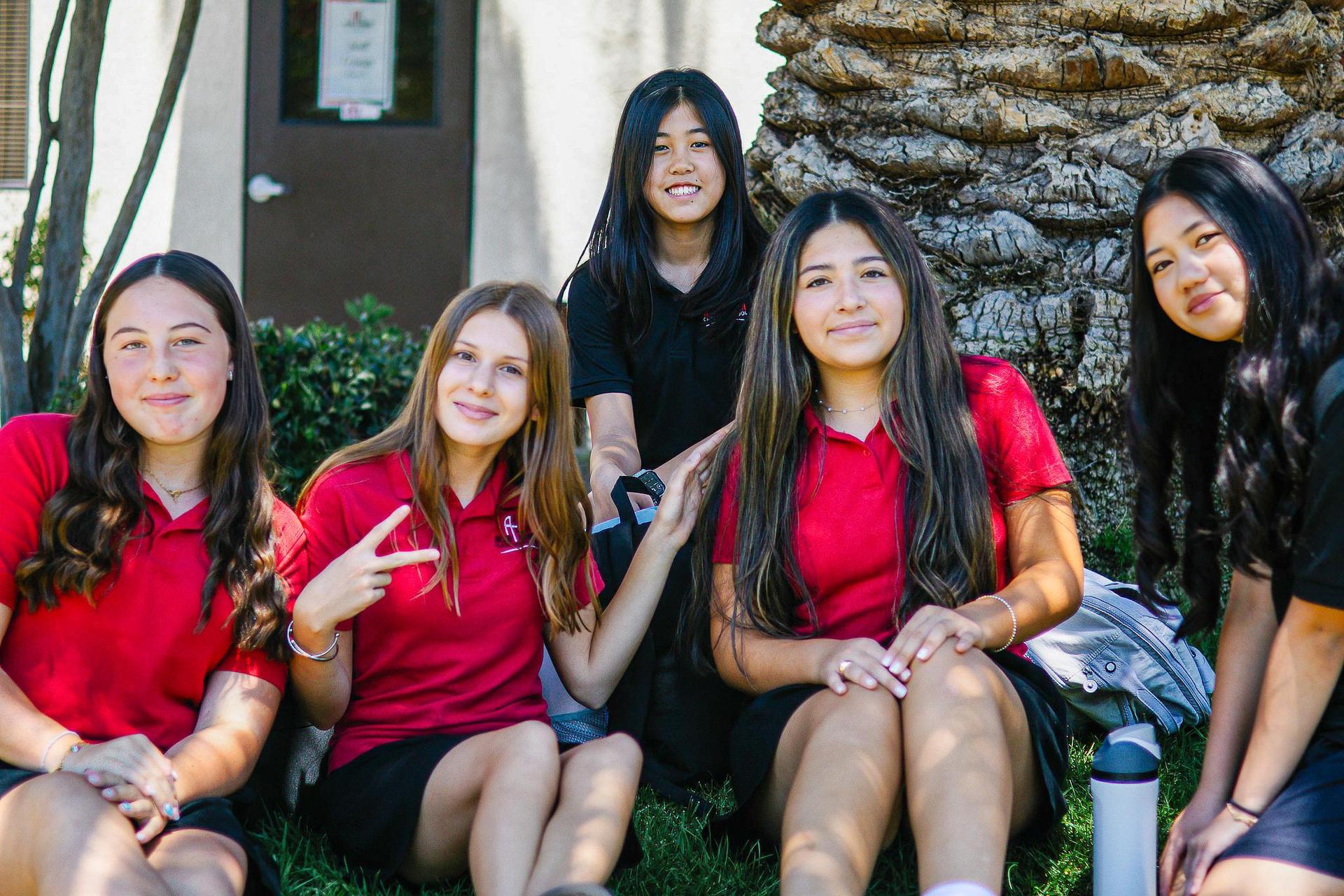 A group of middle school girls sitting in the shade.
