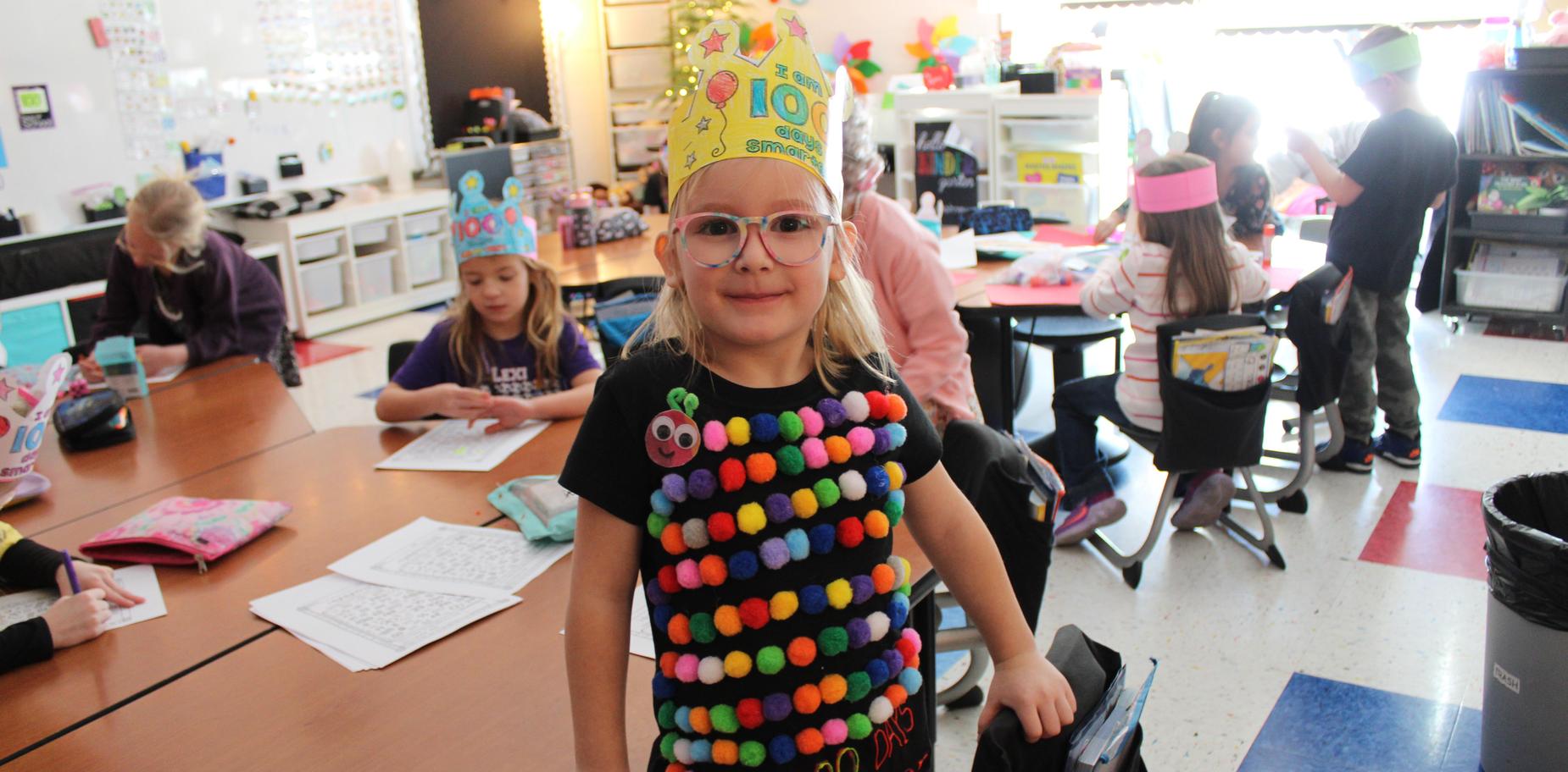 girl wearing a paper crown and a shirt with fuzz ball caterpillar on it
