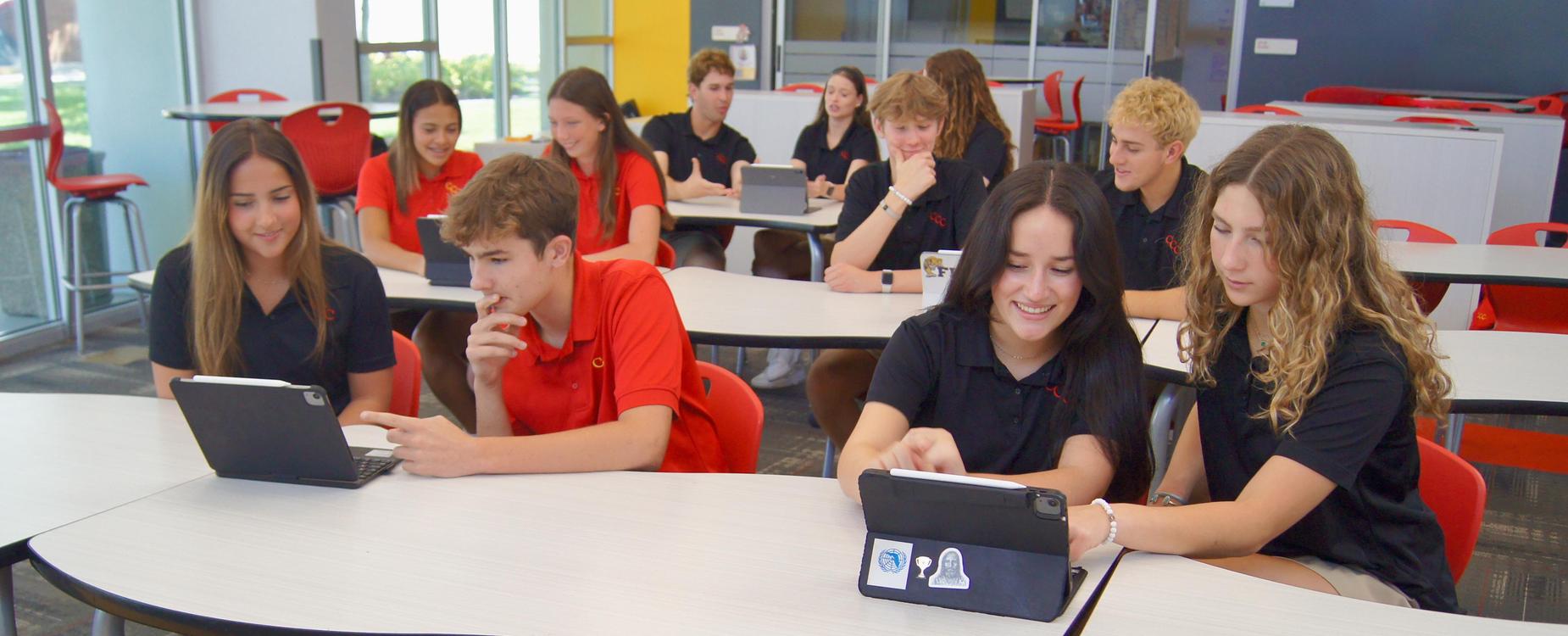 A large group of students use iPads in pairs