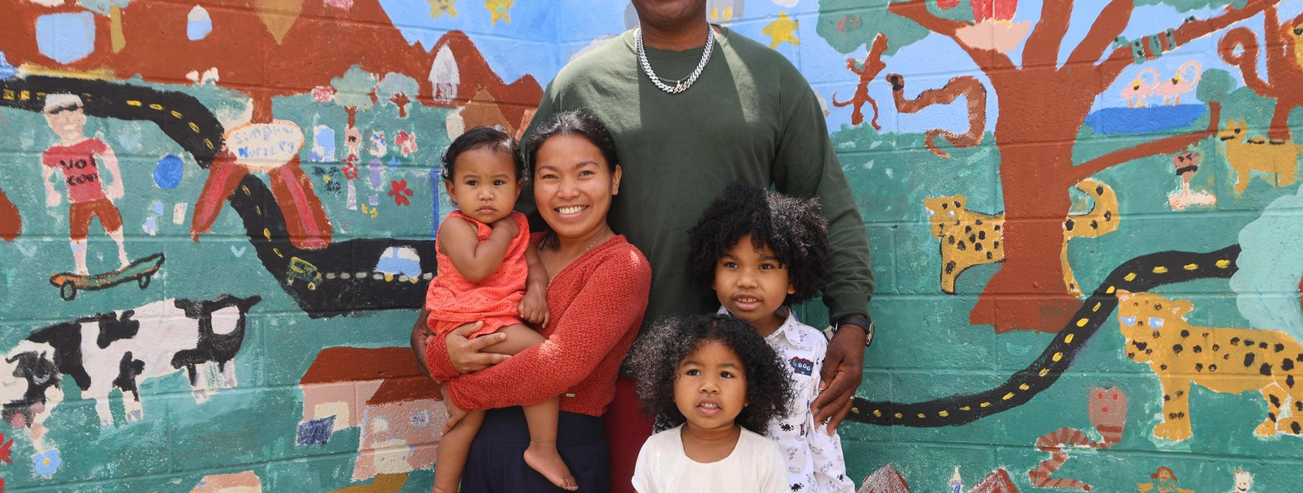 Family portrait with children, man and woman in front of a colorful mural.