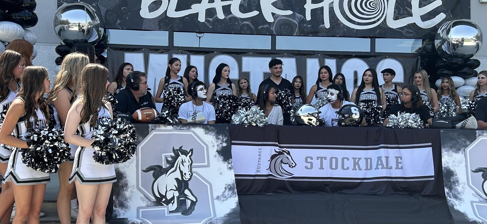 Cheerleaders and announcers gathered for an event at the Black Hole, with decorations.