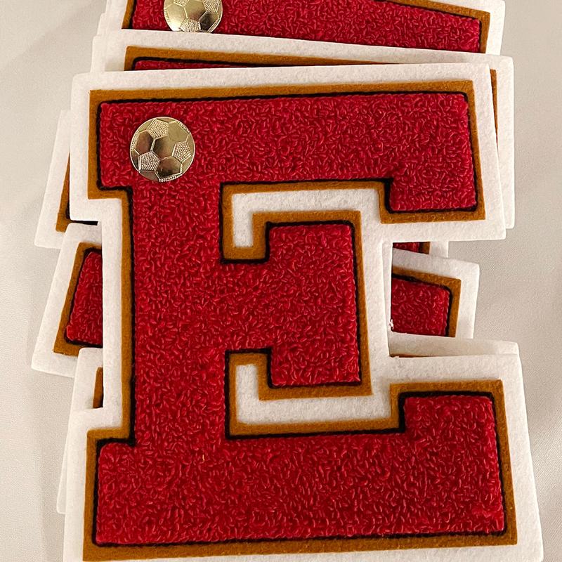 Stack of red felt letter 'E' patches with gold soccer ball buttons.