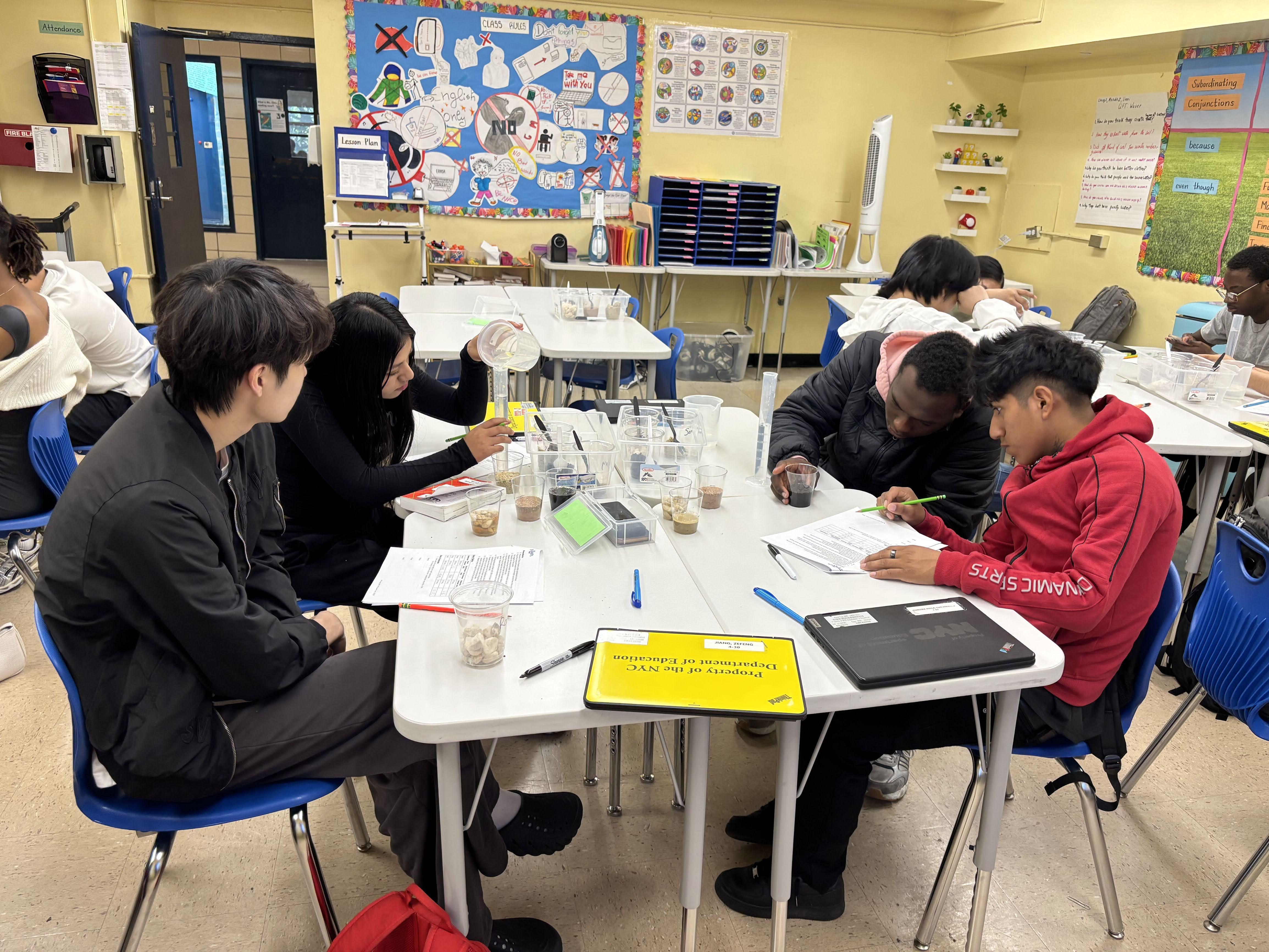 Students in a classroom — laptops open, discussing, collaborating and learning together
